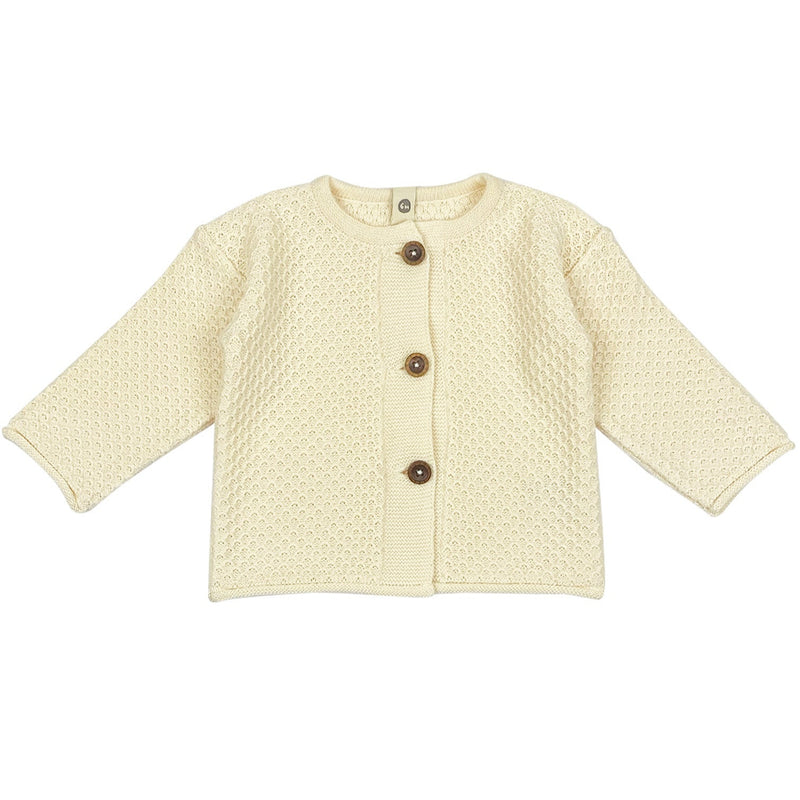 A beige knitted cardigan with four coconut buttons and a boxy shape, displayed against a white background.