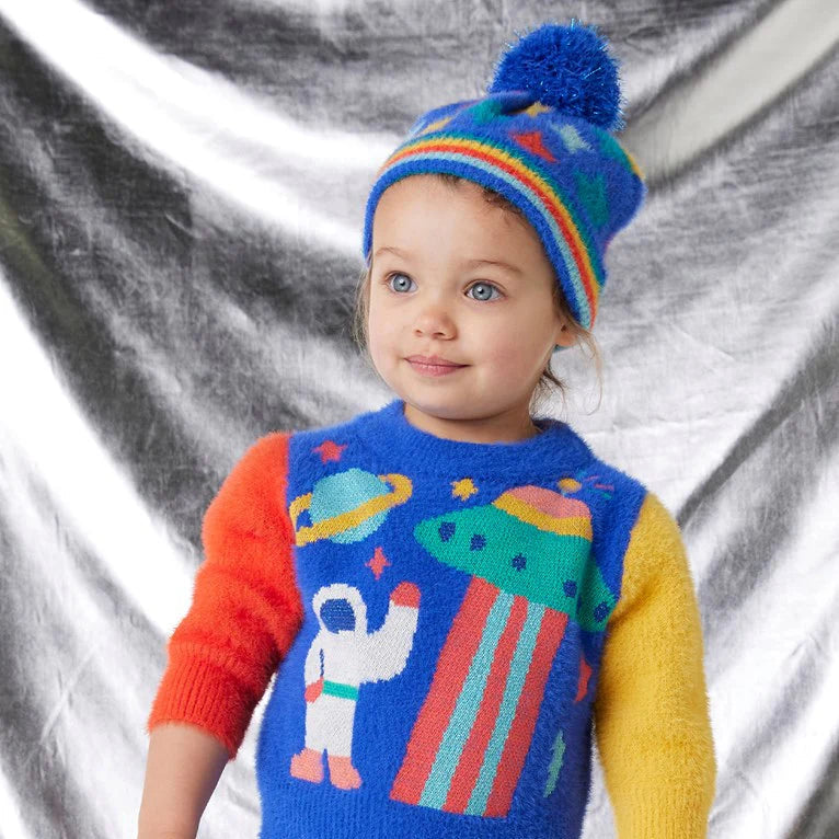 Child wearing a colorful sweater and hat with space-themed design against a silver background