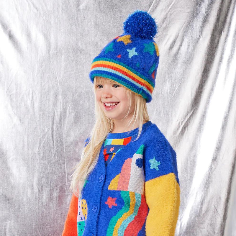 Child wearing a colorful sweater and hat with star patterns against a silver background
