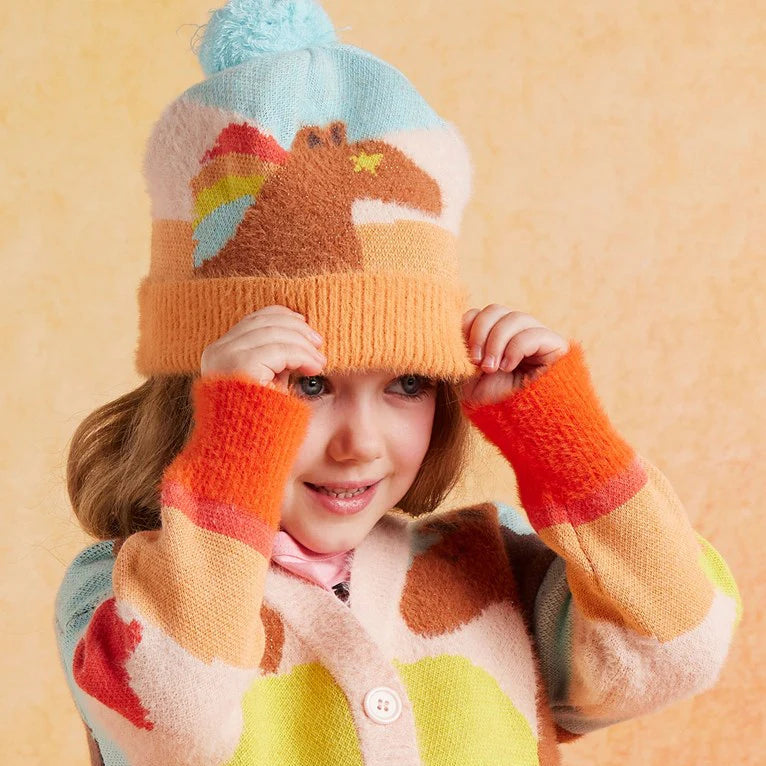 Child wearing a colorful knit hat and sweater against a yellow background